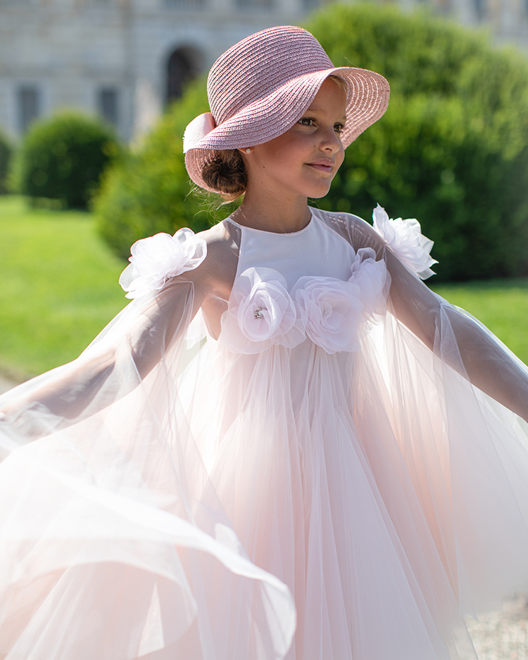 Child in a pink tulle cape gown with floral appliqué and straw hat