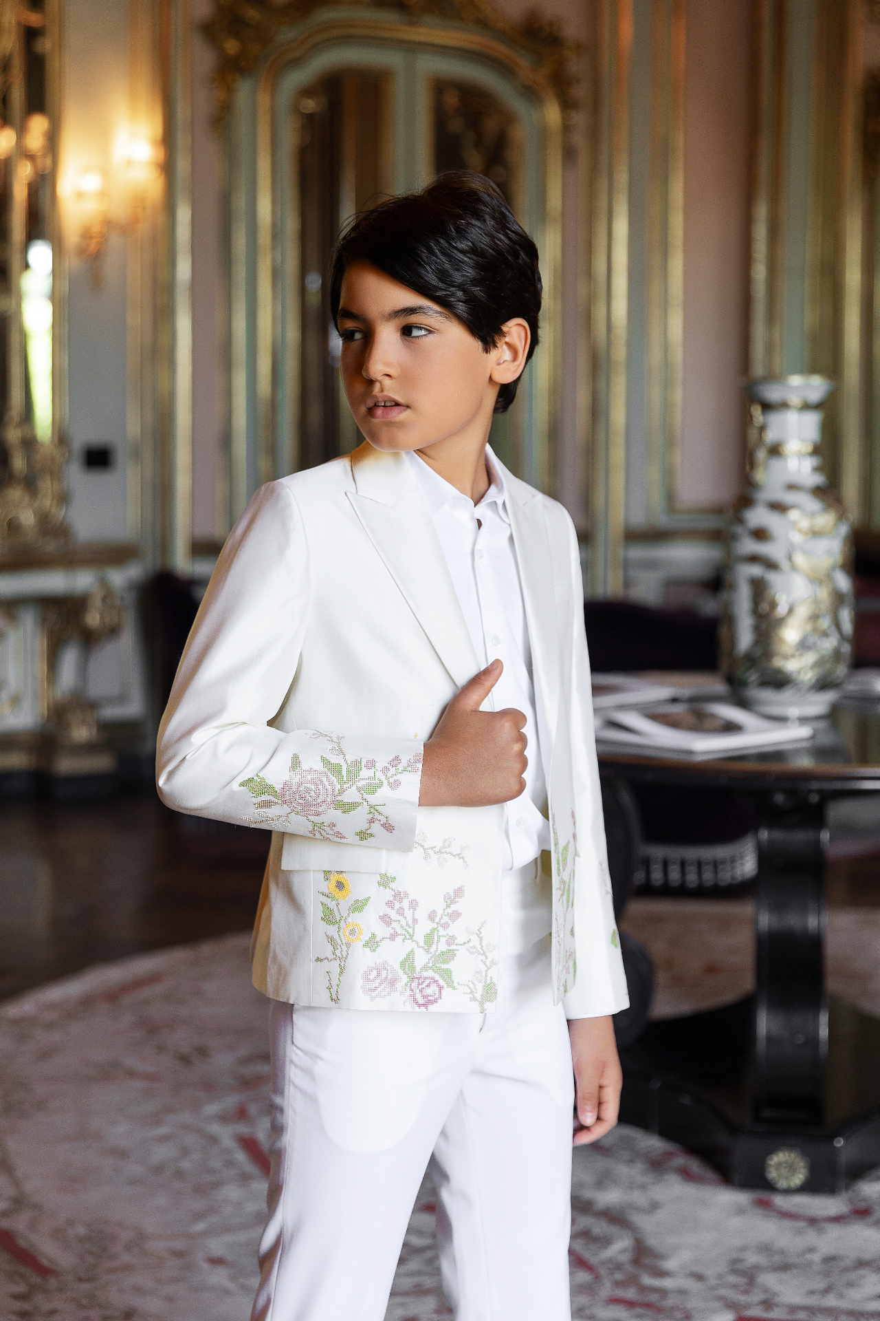 Boy in a white tailored suit with cross-stitch floral embroidery