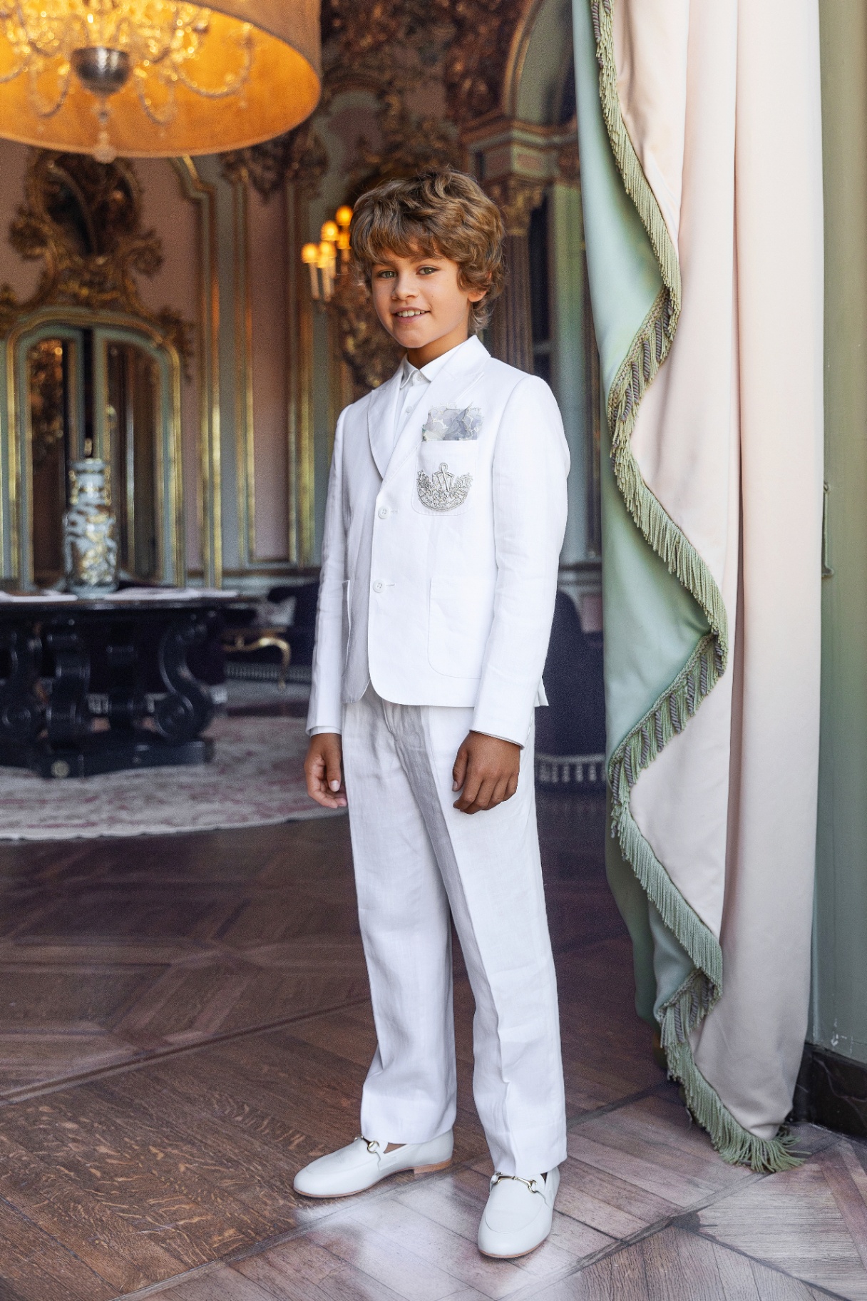 Boy in a white linen suit with embroidered pocket crest